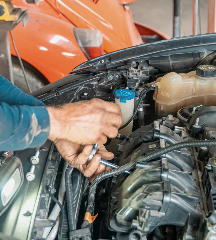 Mechanic's hands working on a car engine with a spanner